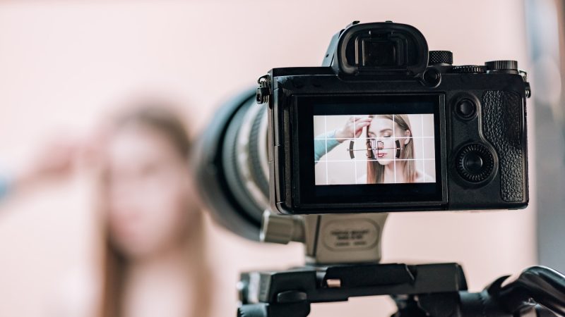 Selective focus of assistant working with attractive model on camera display in photo studio